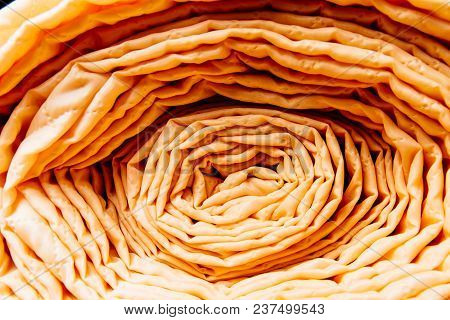 The Material Is Yellow In Color And Strongly Twisted In A Roll