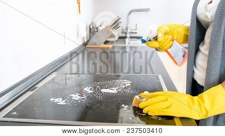 Closeup Photo Of Young Housewife Using Detergent Spray To Clen Electric Hob