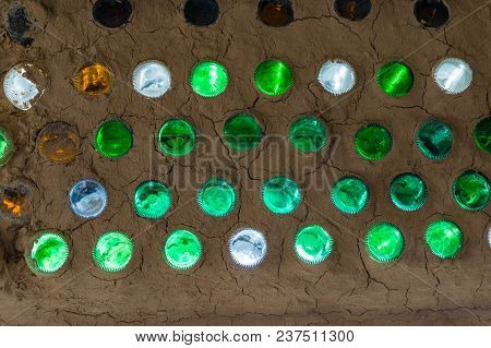 Colorful Sunlit Bottles In A Clay Cob Wall, Bottle Wall Mosaic. Ecological Building From Natural And