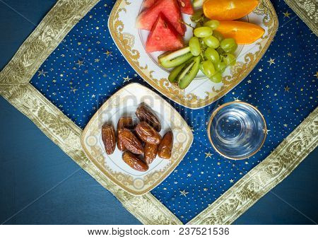 Fresh mixed fruit and sweet dates along with glass of drinking water shot from above. A healthy and nutritious food for breaking fast during holy month of Ramadan.