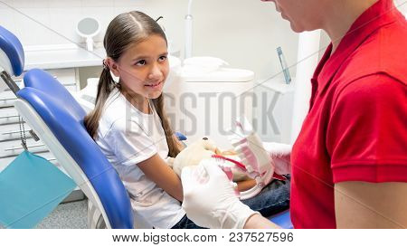 Pediatric Dentist Educating Girl About Proper Tooth Cleaning