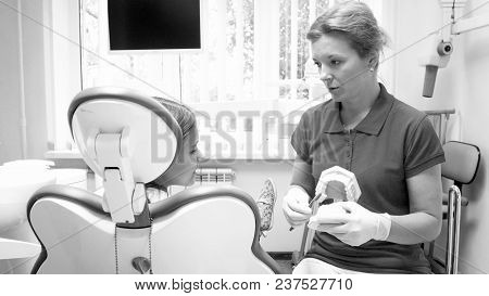 Monochrome Portrait Of Female Dentist Explaining Importance Of Teeth Hygiene