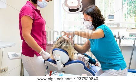Dentist In Portective Mask And Eyeglasses Treting Patient Sitting In Chair