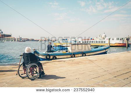 Disabled Person In Wheelchair Looking At Sea. Venice, Italy.