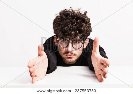 Portrait Of A Self-confident Young Man In A Studio, Stretching His Hands.