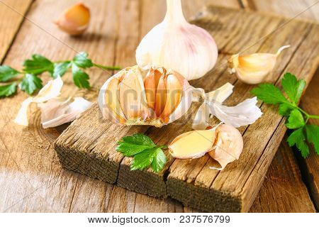 Heads Of Garlic With Parsley On A Wooden Table