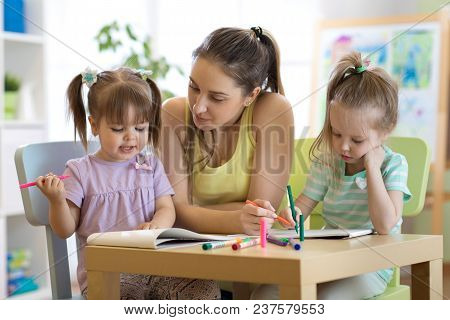 Kindergarten Female Teacher Helping Kids In Artclass