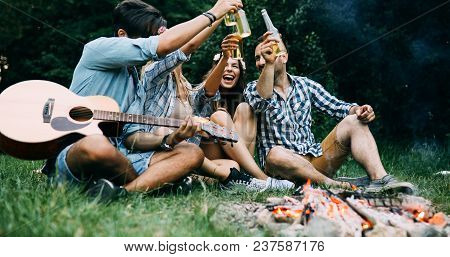 Group Of Friends Camping, Sitting Around Camp Fire, Playing Guitar