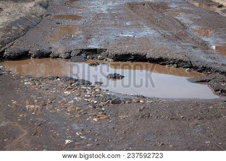 The Bad Asphalted Road. Big Pothole Filled With Water. Dangerous Destroyed Roadbed. Mirror Reflectio