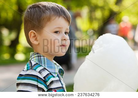 Adorable Little Boy Eating White Sweet Cotton Candy.
