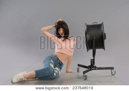 Young Sexy Female Model Posing With Working Wind Machine On Grey Background