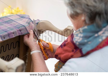 Detail Of Senior Woman Re-upholstering Chair At Home