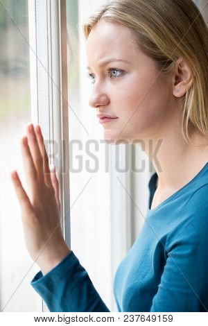 Sad Young Woman Suffering From Depression Looking Out Of Window