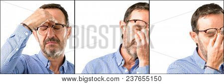Middle age handsome man closeup with sleepy expression, being overworked and tired, rubbes nose because of weariness