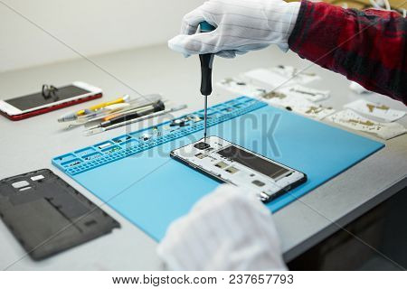 Cropped Shot Of Male Technician In Antistatic Gloves Using Screwdriver To Disassemble Borken Mobile 