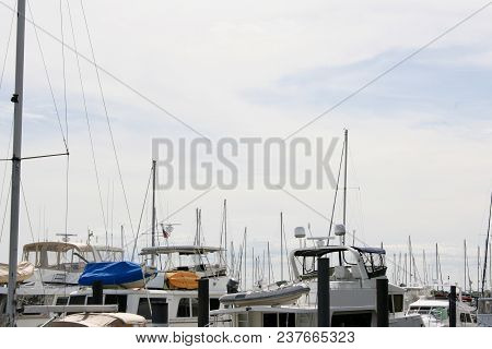 White Sailboats Filling A Harbor With A Spot Of Tan, Blue, Orange, Red, And Green Small Boat Covers 