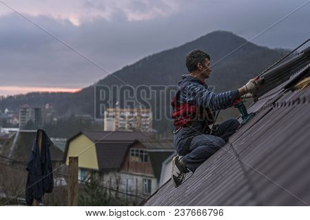 Roofer Assembles Sheet Metal On The Roof. Roofers On The Roof.