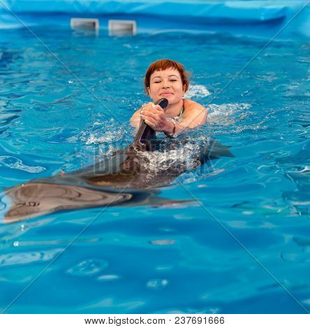 Young Happy Girl Swimming With Dolphin