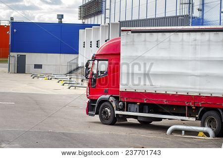 Truck Near Logistics Center At Unloading Or Loading Of Cargo Into Container. Transportation Of Goods