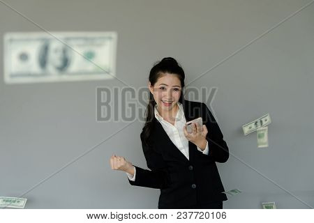 Young Business Woman Using Smart Phone To Make Money, Dollar Floating In The Air. Fists Up, Air Punc