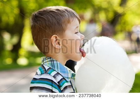 Adorable Little Boy Eating White Sweet Cotton Candy. Happy Child Eating Candy Floss In The Park At S