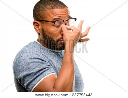 African american man with beard with sleepy expression, being overworked and tired, rubbes nose because of weariness isolated over white background