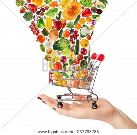 Female Hand Holding Grocery Cart With Vegetables And Fruits Falling In It Isolated On White. Healthy