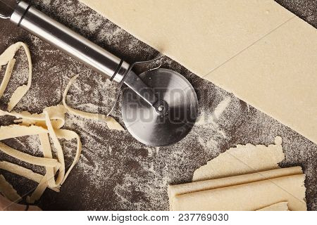 Raw Dough And Wheel Cutter On Kitchen Table, Top View. Preparation Of Italian Pasta, Copy Space