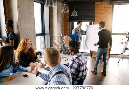Blond Chief In Grey Dress Is Telling Jokes While Meeting With Colleagues In The Lft Office