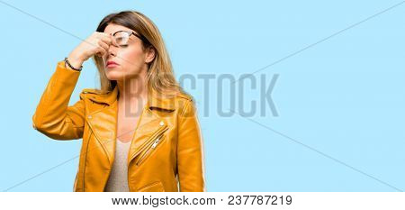 Beautiful young woman with sleepy expression, being overworked and tired, rubbes nose because of weariness