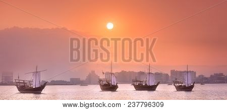 Traditional Arabic Dhow Boats In Doha Harbour During Orange Sunset, Qatar.