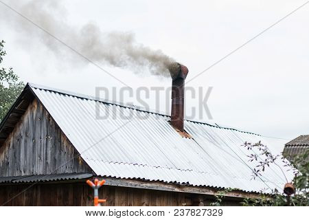 Smoke Comes From The Chimney Of The House. Country House. Smoke In The Sky