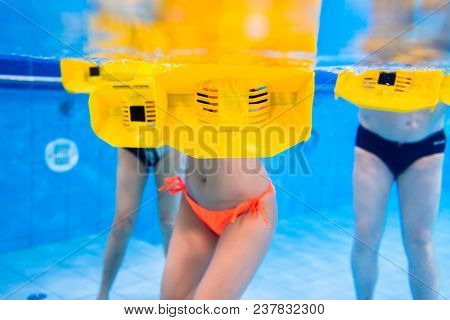 Group in water physical therapy training with resistance devices, underwater shot