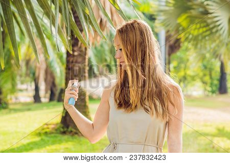 Woman Spraying Insect Repellent On Skin Outdoor.