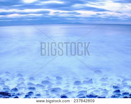 Blue Sunset At Rocky Coast Of Sea. Slow Shutter Speed For Smooth Water Level And Dreamy Effect