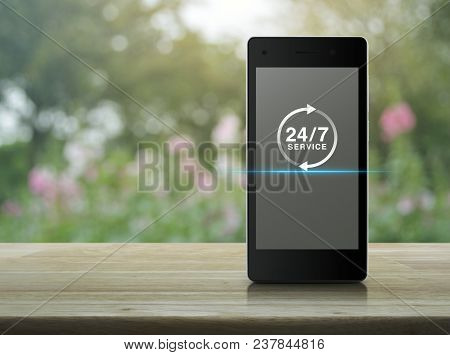 24 Hours Service Icon On Modern Smart Phone Screen On Wooden Table Over Blur Pink Flower And Tree, F