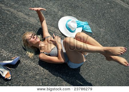 Donna sdraiata su una strada nel deserto schermatura sole con la mano