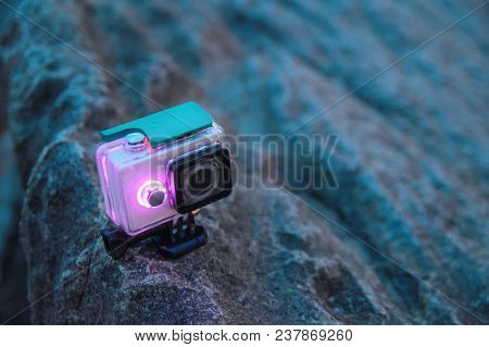 Action Camera Stands On A Rock. Video Camera In Waterproof Protective Box With Luminous Diode Indica