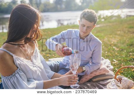 Happy Couple On Picnic. Celebrating Their Special Date. Young Couple Sitting On Plaid With Fruits Wi