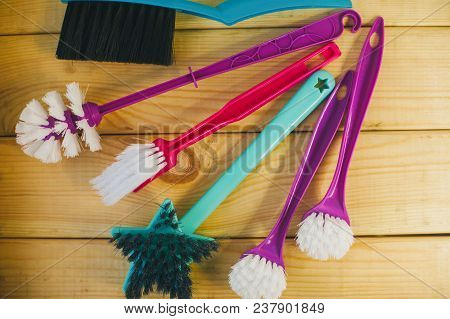 Cleaning House Or Office Concept. A Set Of Colorful Plastick Brushes On A Light Wooden Background, T