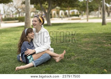 Happy Girls Sitting On The Grass.