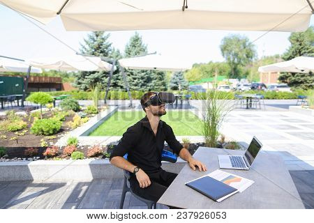 Caucasian Businessman Enjoying With Virtual Reality Glasses, Working With Laptop And Papers Under Be