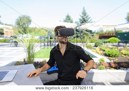 Caucasian Businessman Working With Papers And Laptop, Enjoying Virtual Reality Glasses In Open Air .