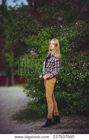 Pretty Woman Blonde On A Rustic Road Is Happy, Against A Background Of Lots Of Green Trees, A Beauti