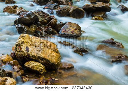 Motion Blurred Rapids Of Mountain River And Wet Boulders Closeup