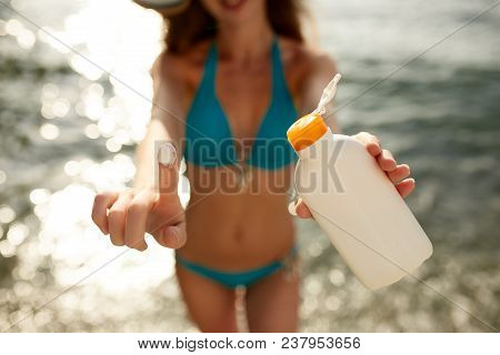 Closeup Of Smiling Caucasian Woman Showing Sunscreen Oil Bottle And Using Suntan Cream Smear On Fing