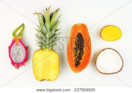 Tropical Fruit Flat Lay With Cut Pineapple, Dragon Fruit, Papaya, Mango, And Coconut On A White Back