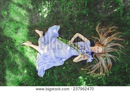 Attractive Young Girl With Blonde Dren Hair And Natural Make-up Smelling Blue Purple Iris Flowers Ly