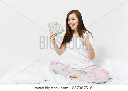 Young Fun Happy Woman Sitting In Bed With White Sheet, Pillow, Wrapping In Blanket On White Backgrou