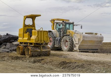 Yellow Loader And Small Road Roller At A Loamy Construction Site